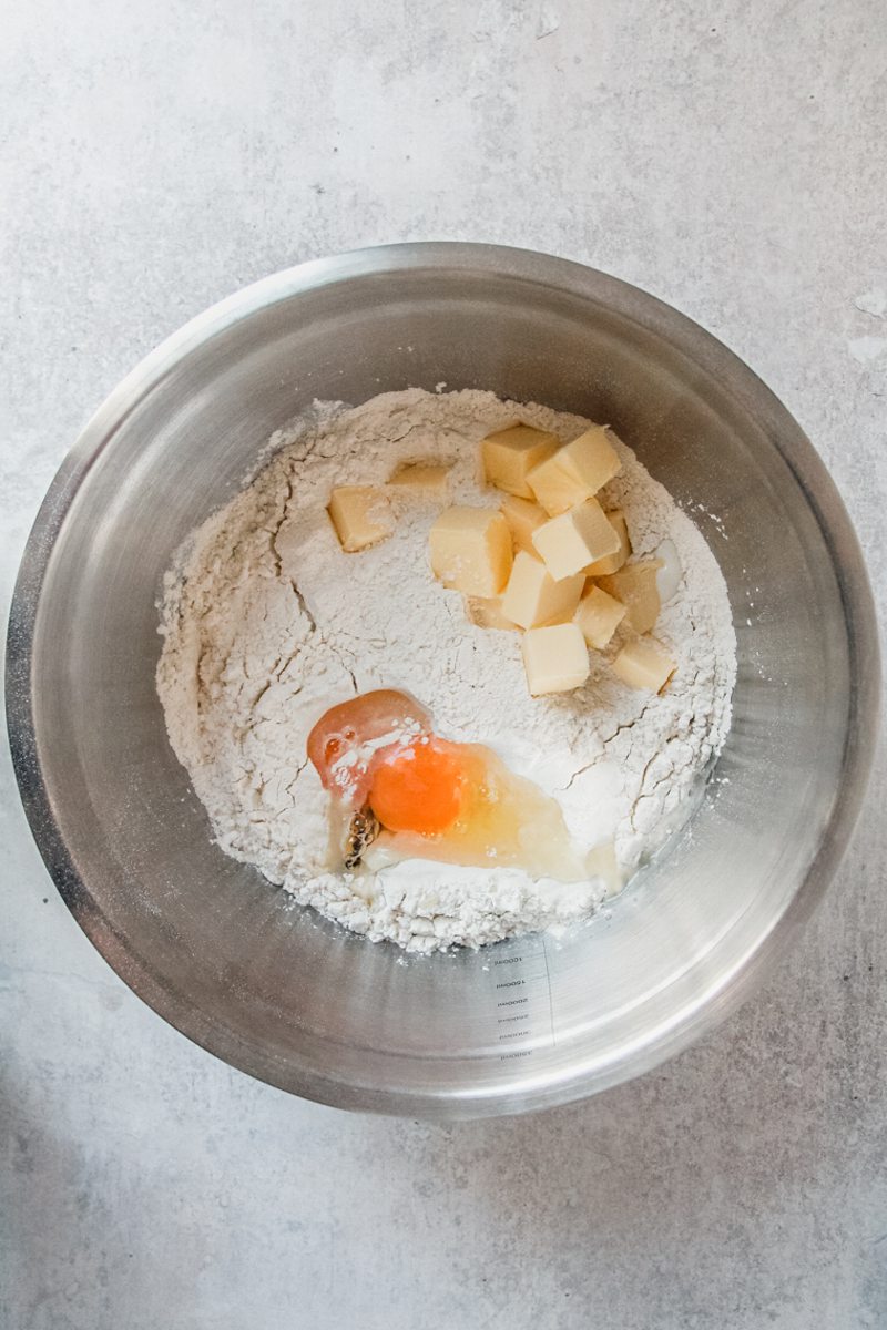 Kolache dough ingredients sit in a stainless steel bowl on a gray surface.