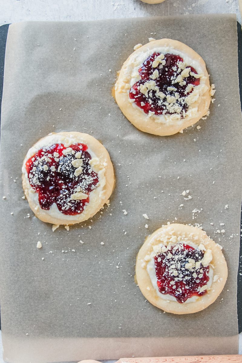 Kolaches sit on a lined baking tray.