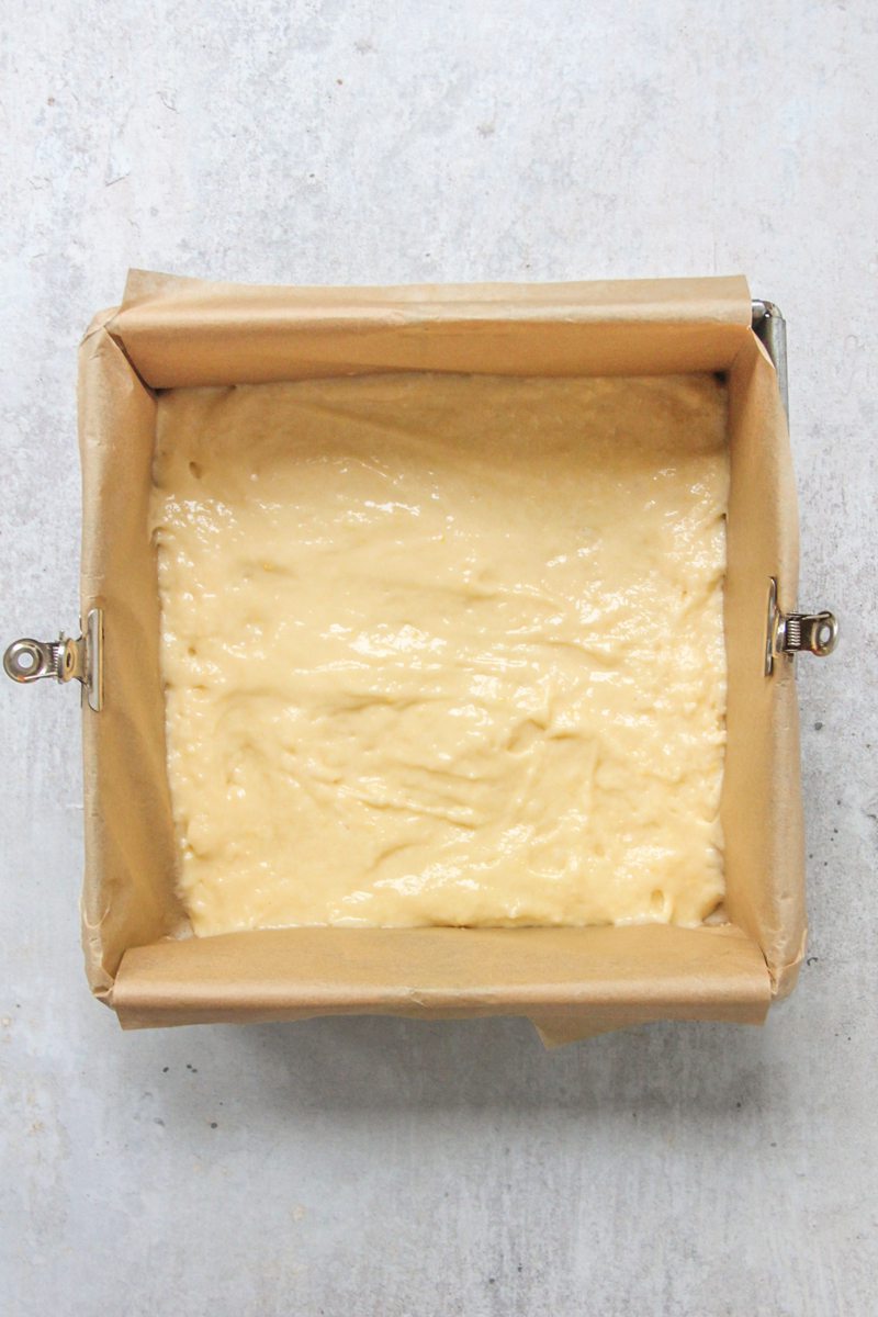 A kefir dough mixture sits in a square tin lined with parchment paper on a gray surface.