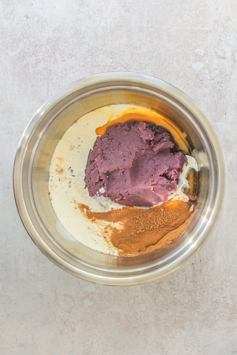 Sweet potato pie bars filling sits in a stainless steel bowl on a gray surface.