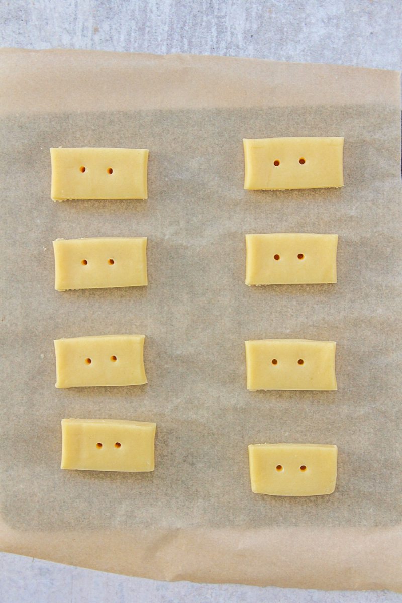 Unbaked shortbread sit on a parchment lined baking tray on a gray surface.
