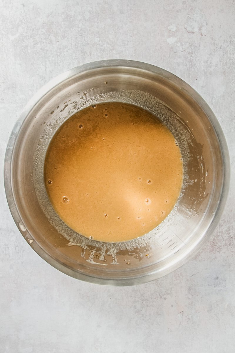 A buttermilk cake mixture sits in a stainless steel bowl on a gray surface.