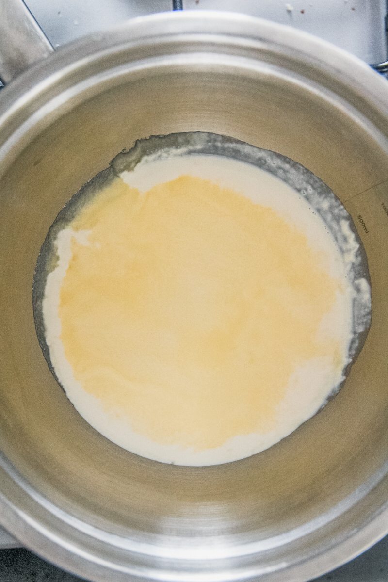 Cream and sugar sits in a stainless steel bowl on a cooker.