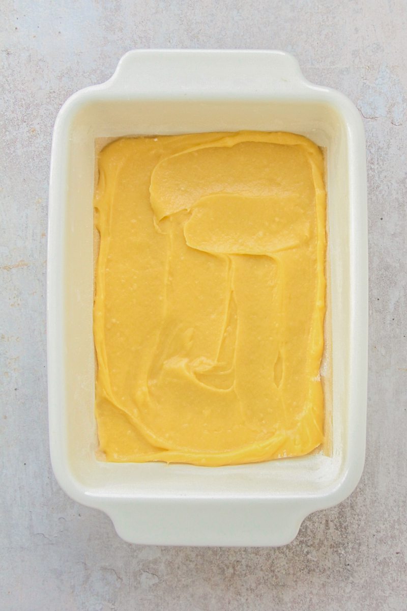 Choux pastry sits spread over a rectangle ceramic dish on a gray surface.