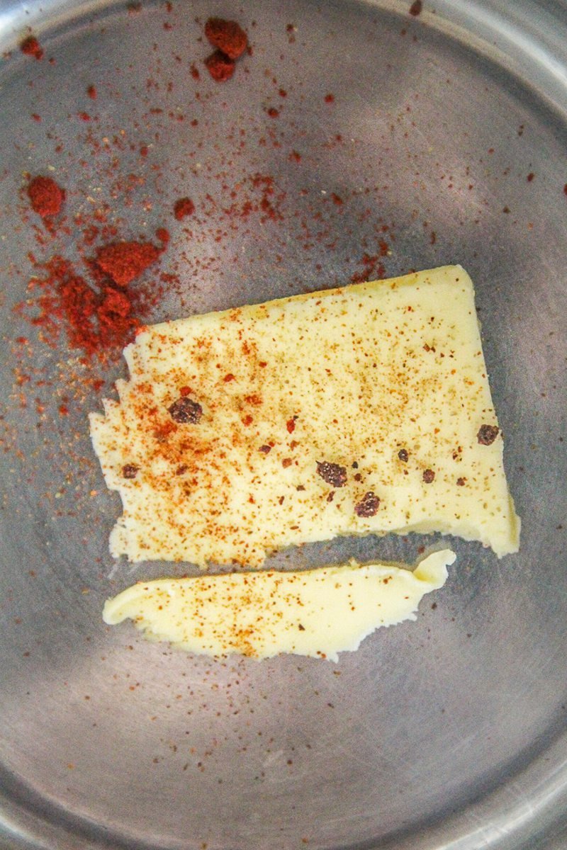 Butter and aleppo pepper sit in a stainless steel saucepan.