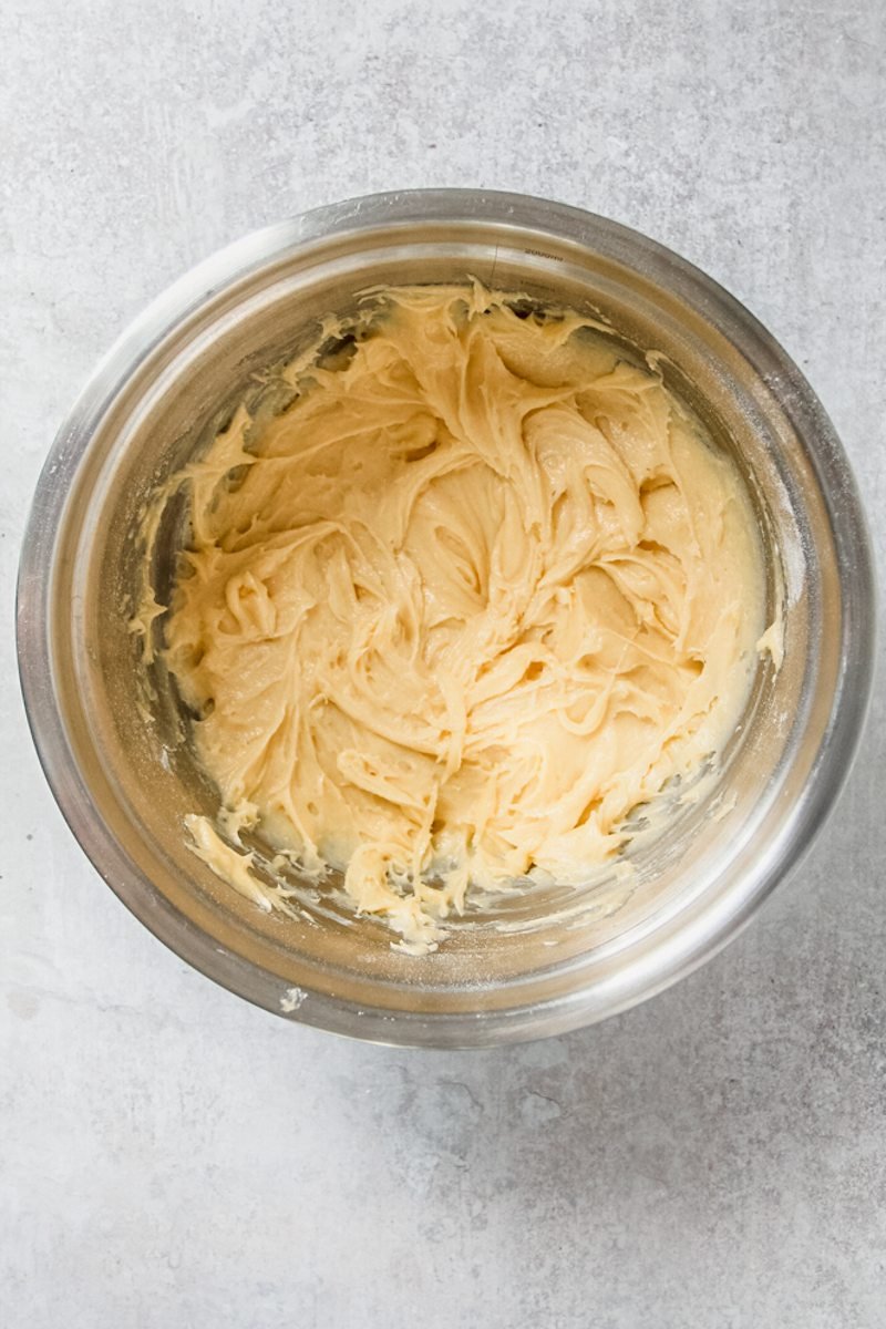 Cake batter sits in a stainless steel bowl on a gray surface.