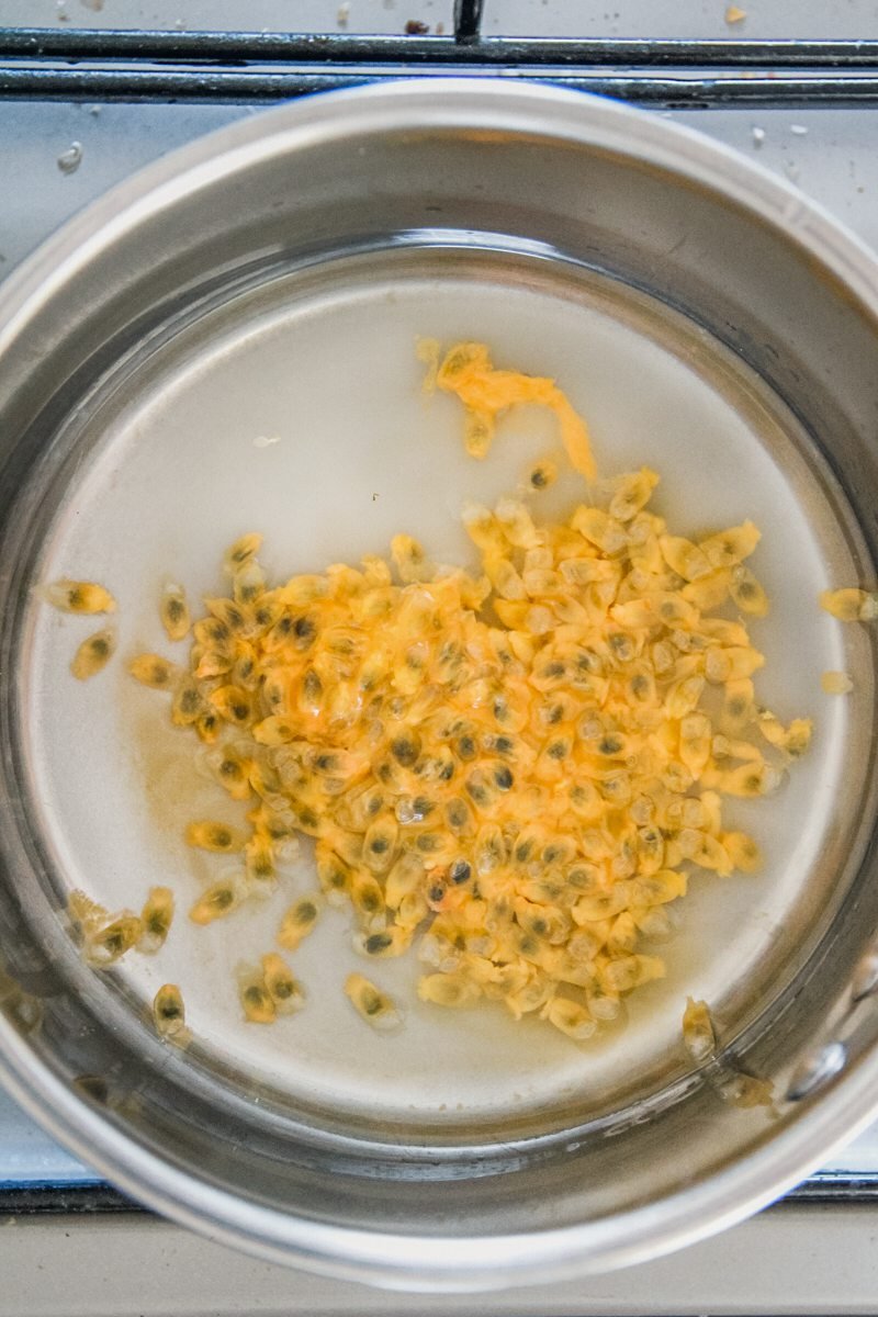 Passionfruit pulp sits in a small saucepan to make a syrup on a cooker.