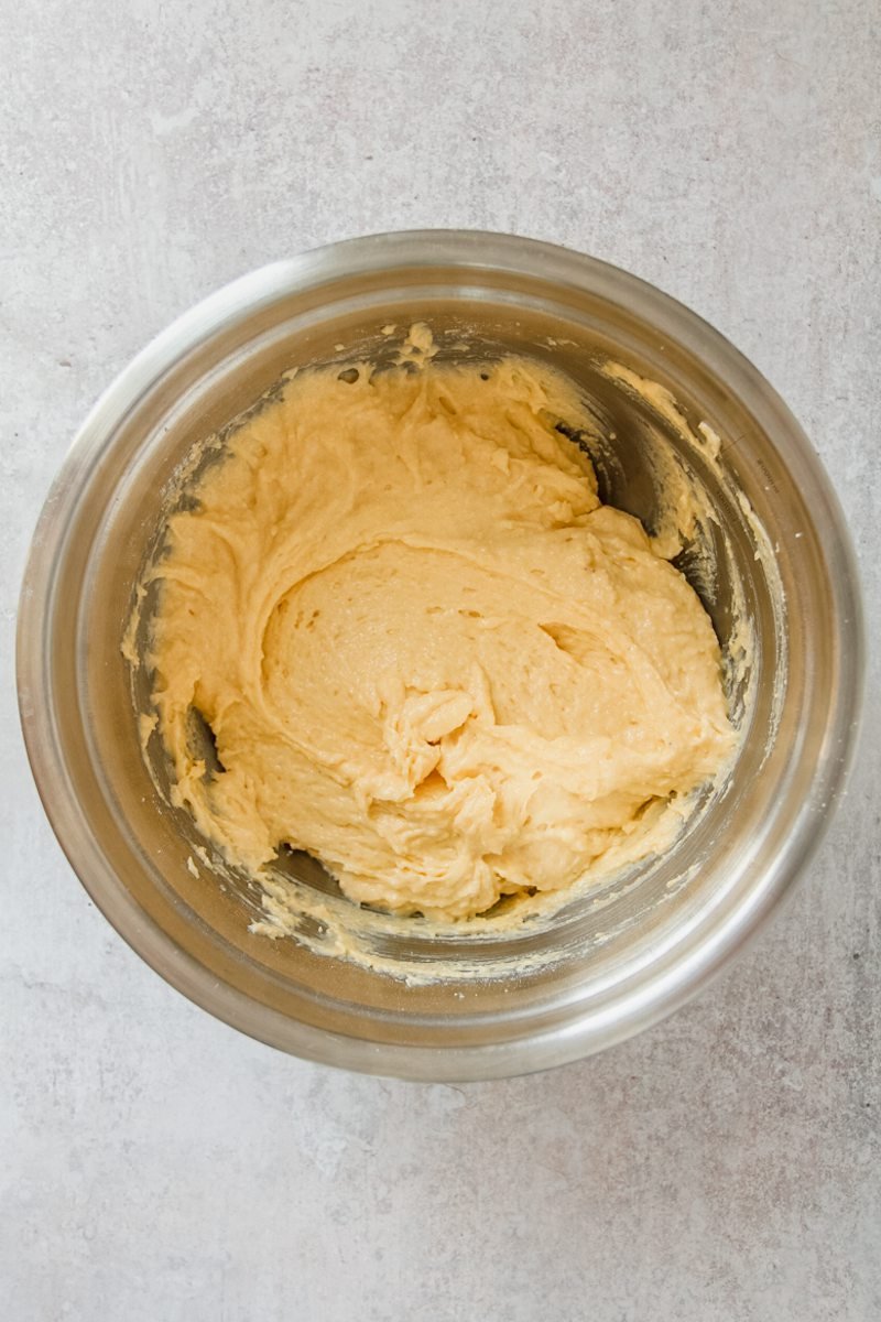 A upside down cake batter sits in a stainless steel bowl on a gray surface.