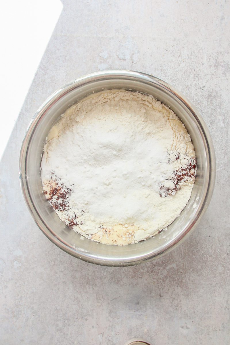 Unmixed cake batter sits in a stainless steel bowl on a gray surface.