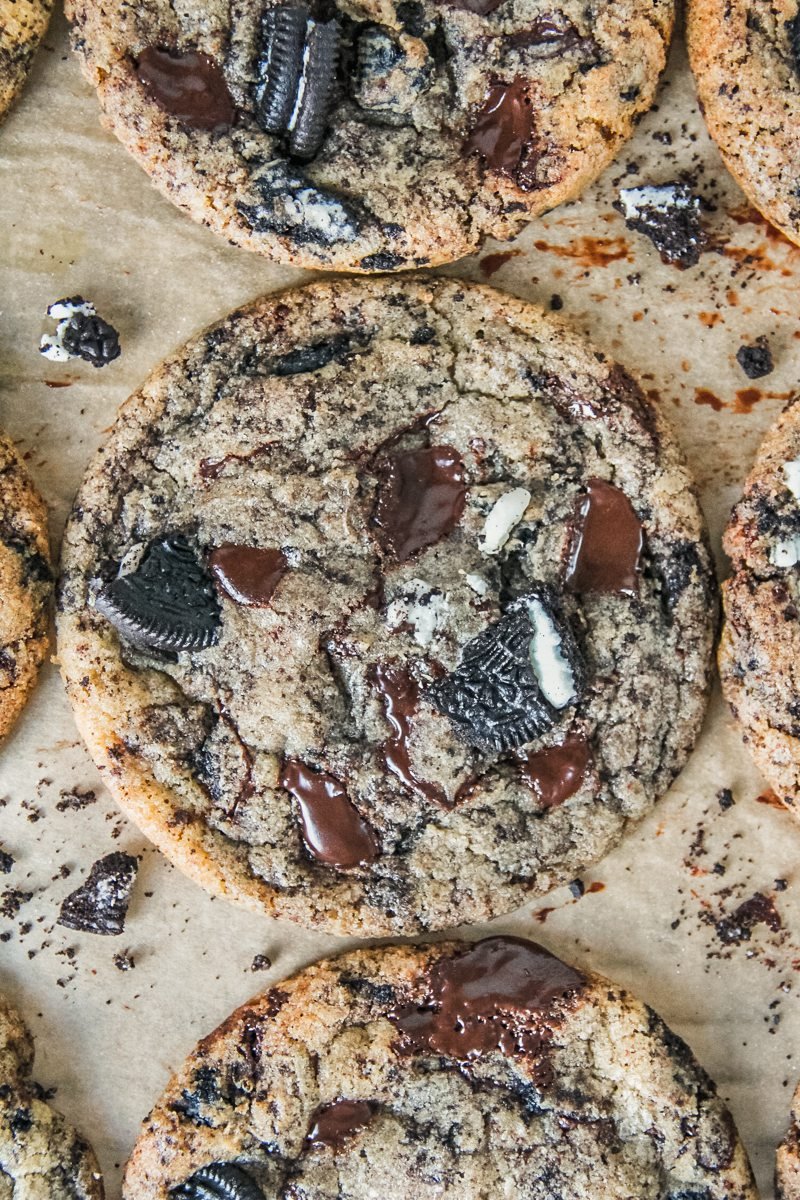 A close up of a cookies and cream cookie sits on parchment paper.