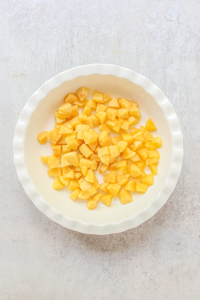 Cubed cookied apples sit in a white ceramic dish on a gray surface.
