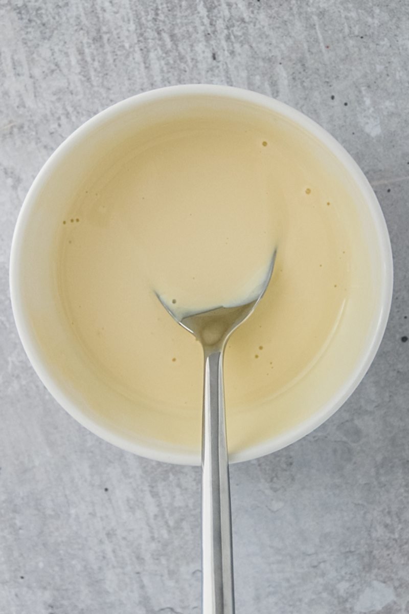 A waldorf salad dressing sits in a white ceramic bowl on a gray surface.