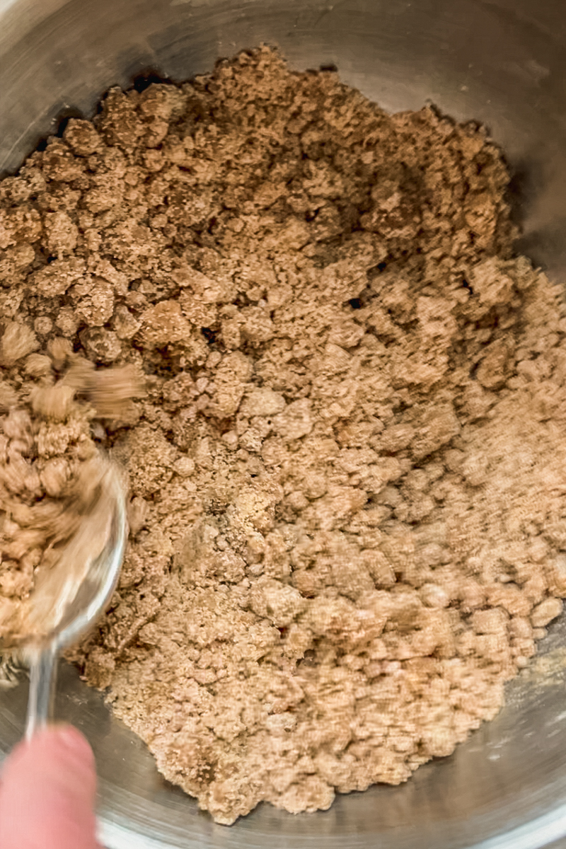 A dairy free streusel is stirred in a stainless steel bowl.