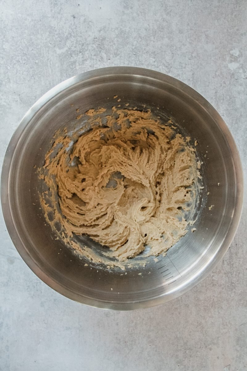 Whipped butter and sugar sit in a stainless steel bowl on a gray surface.