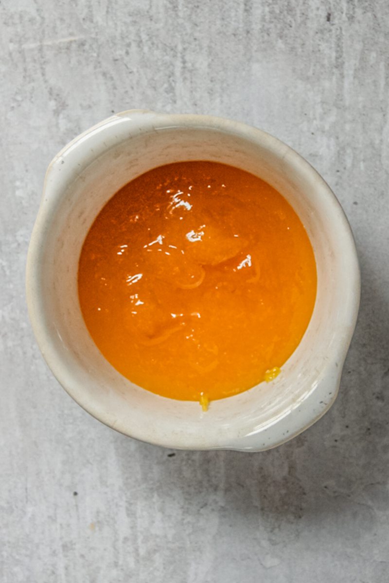 Corn caramel sits in a ceramic ramekin on a gray surface.