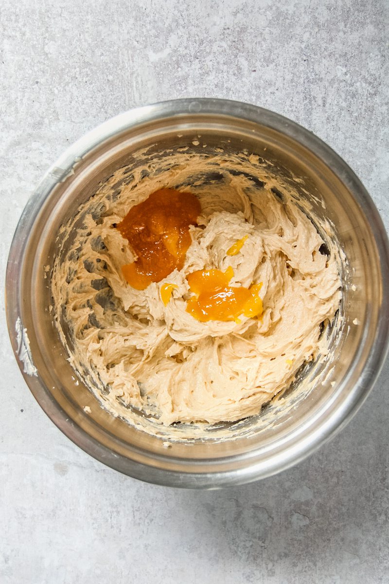 Corn caramel sits on top of a cookie dough in a stainless steel bowl on a gray surface.