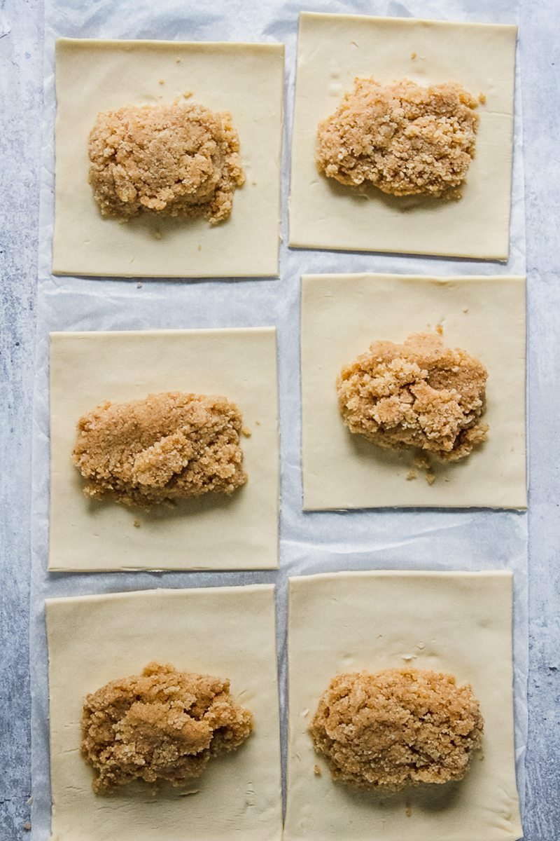 Almond filling sits in the center of square pastries on a gray surface.