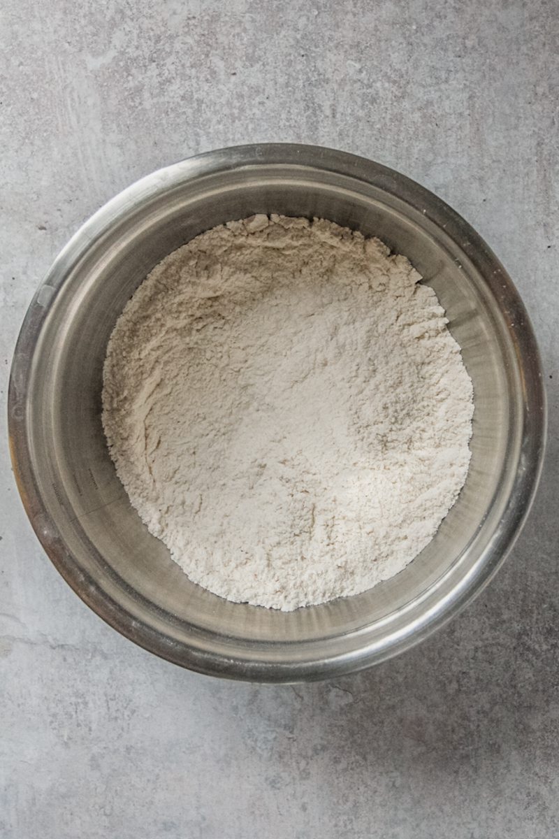 Dry whisked ingredients sit in a stainless steel bowl on a gray surface.