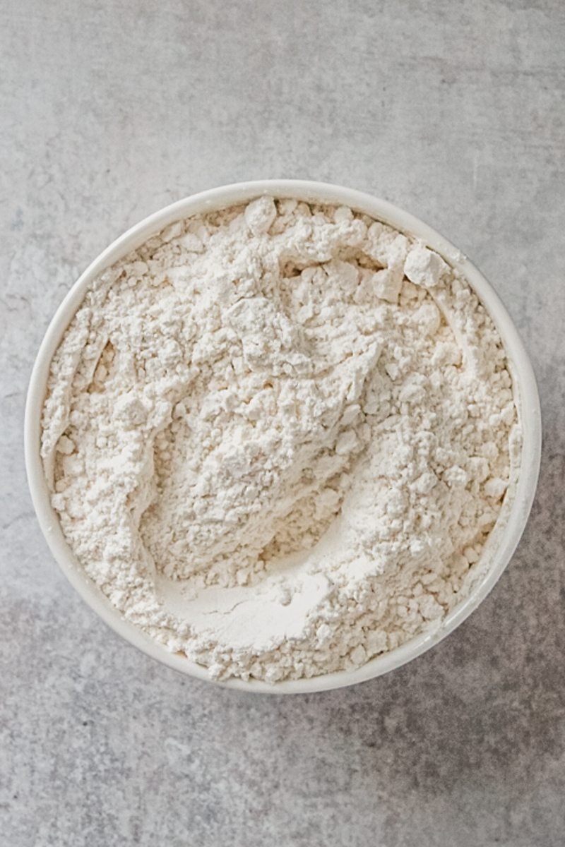 Dry ingredients sit in a white ceramic bowl on a gray surface.