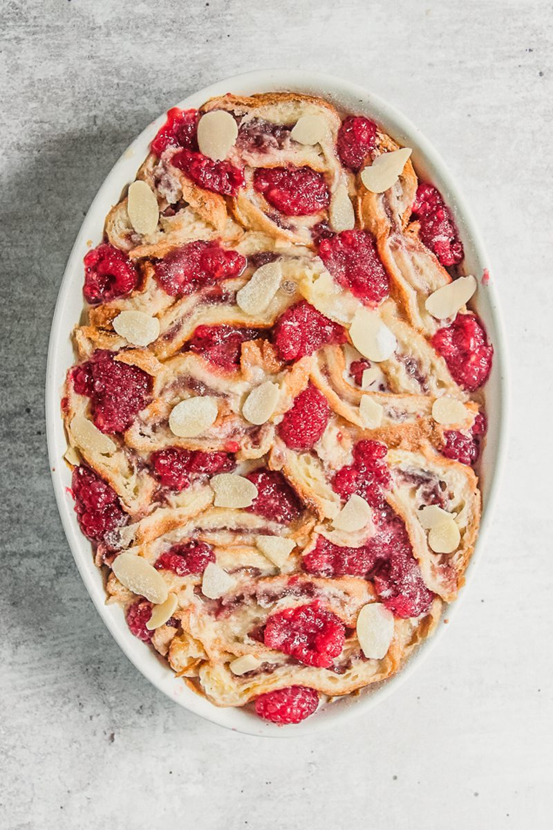 Tightly packed croissant pieces sit in an oval white baking dish on a gray surface.