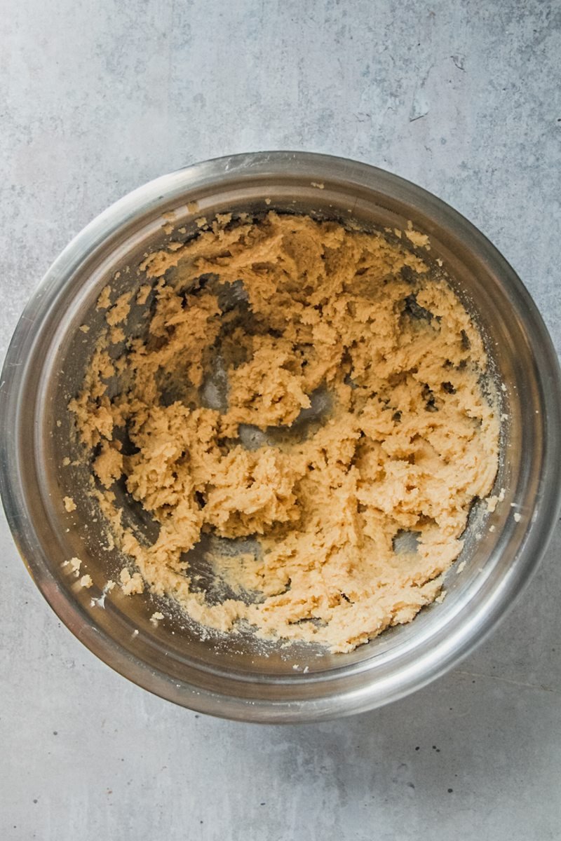 Whipped sugar and butter sits in a stainless steel bowl on a light grey surface.