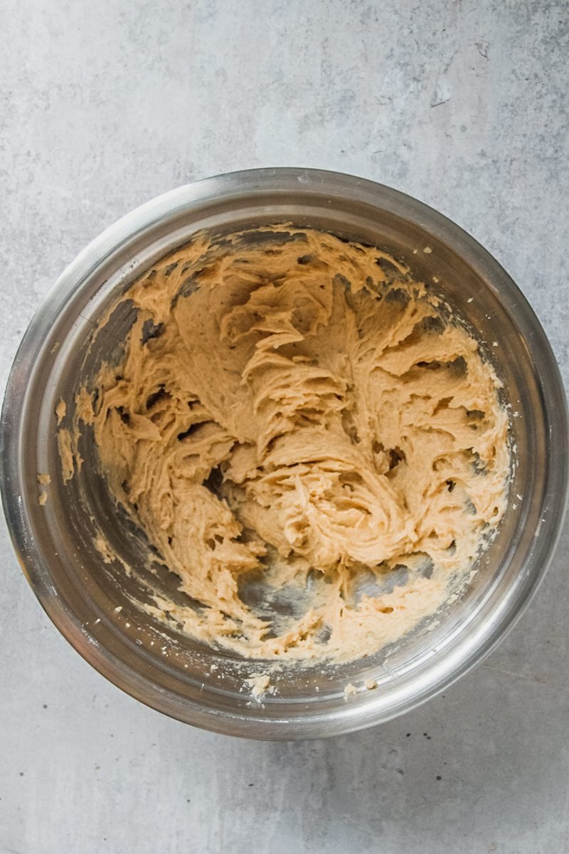 Whipped cookie dough sits in a stainless steel bowl on a light grey surface.