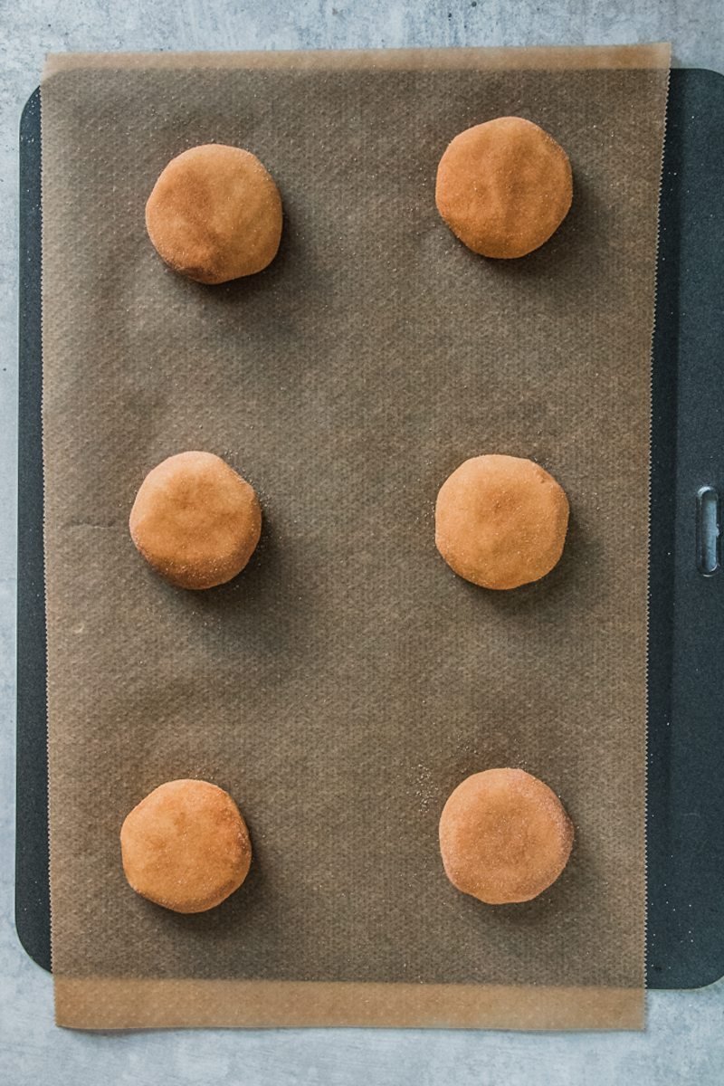 Snickerdoodle cookies sit on a lined baking tray.