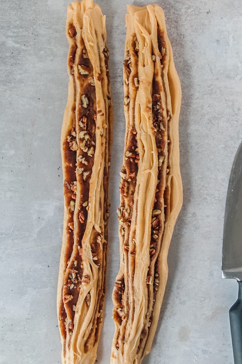 Rolled and halved sweet potato babka sit next to each other on a gray surface.