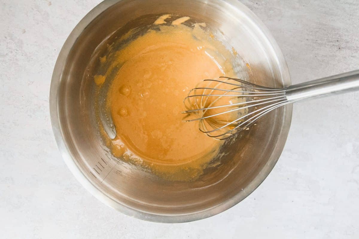 Butterscotch custard base ingredients sit in a stainless steel bowl on a light grey background