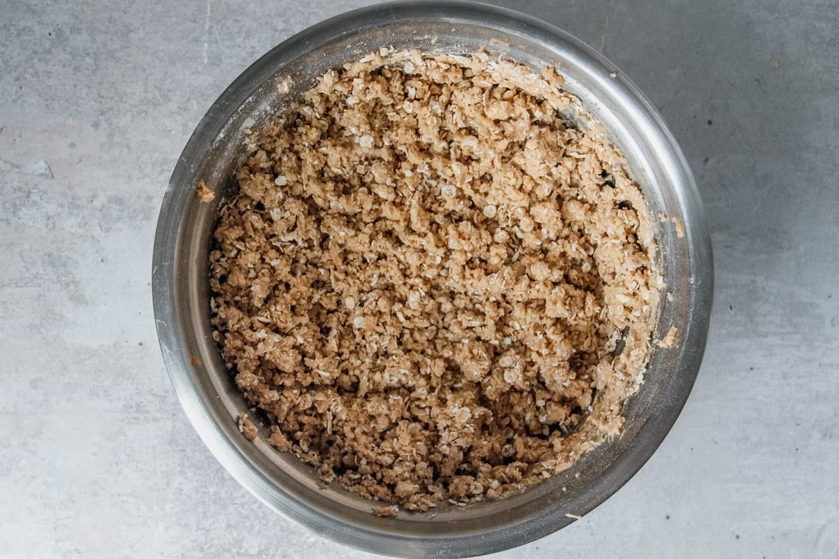 A cinnamon oat mixture sits in a stainless steel bowl on a light grey background.
