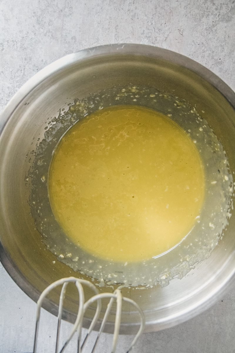 Whipped Olive oil, butter and powdered sugar sit in a stainless steel bowl on a gray surface.