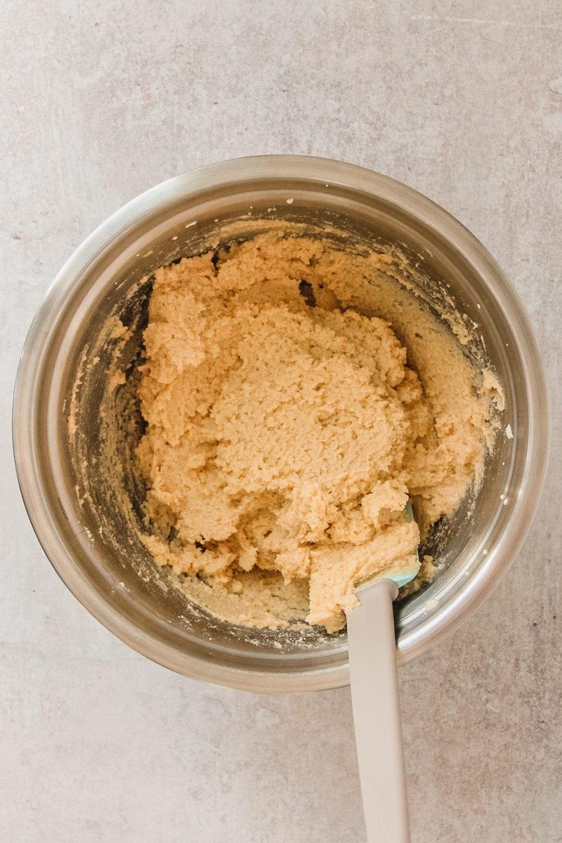 Portuguese Almond cake batter sits in a stainless steel bowl on a gray surface.