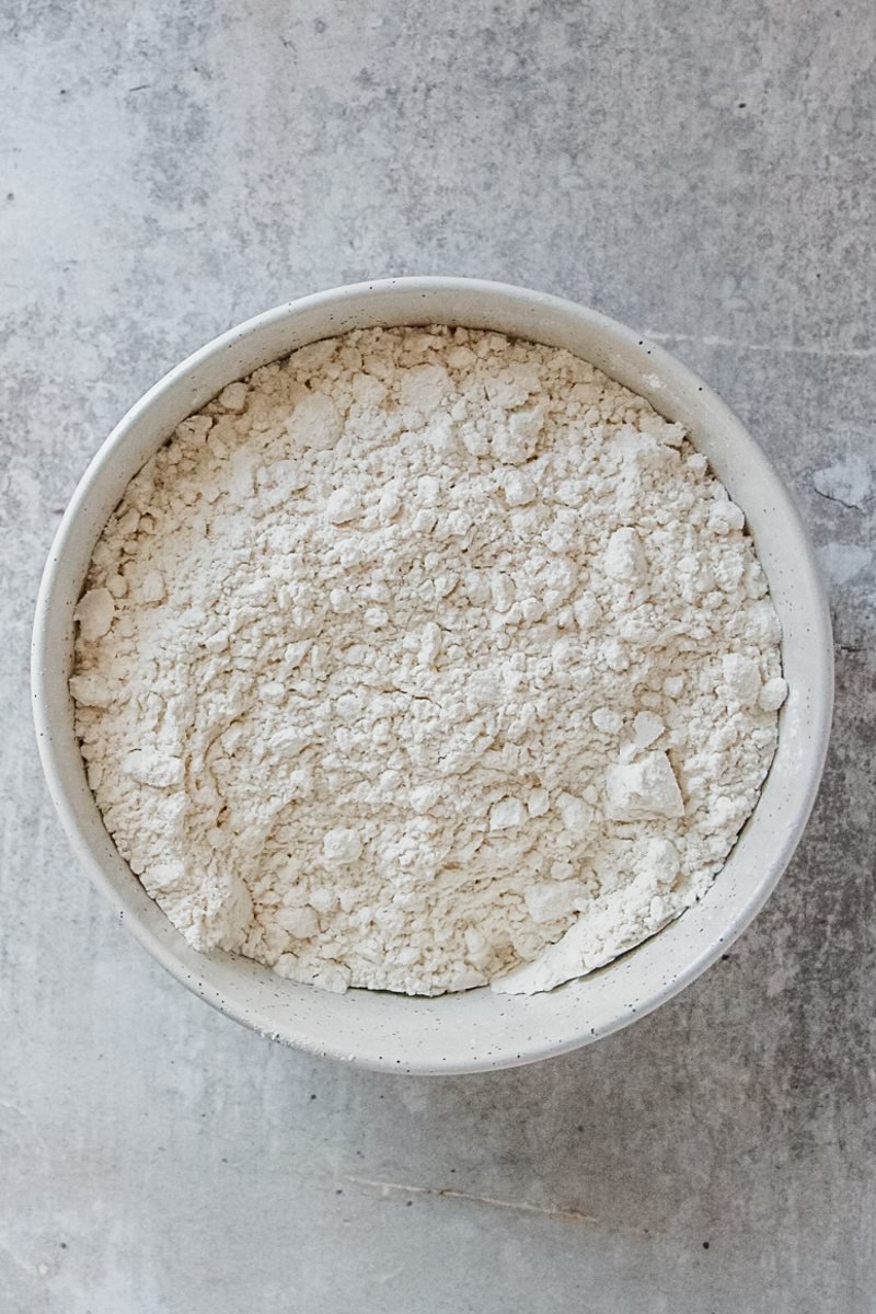 Dry ingredients sit in a white ceramic bowl on a light grey surface.