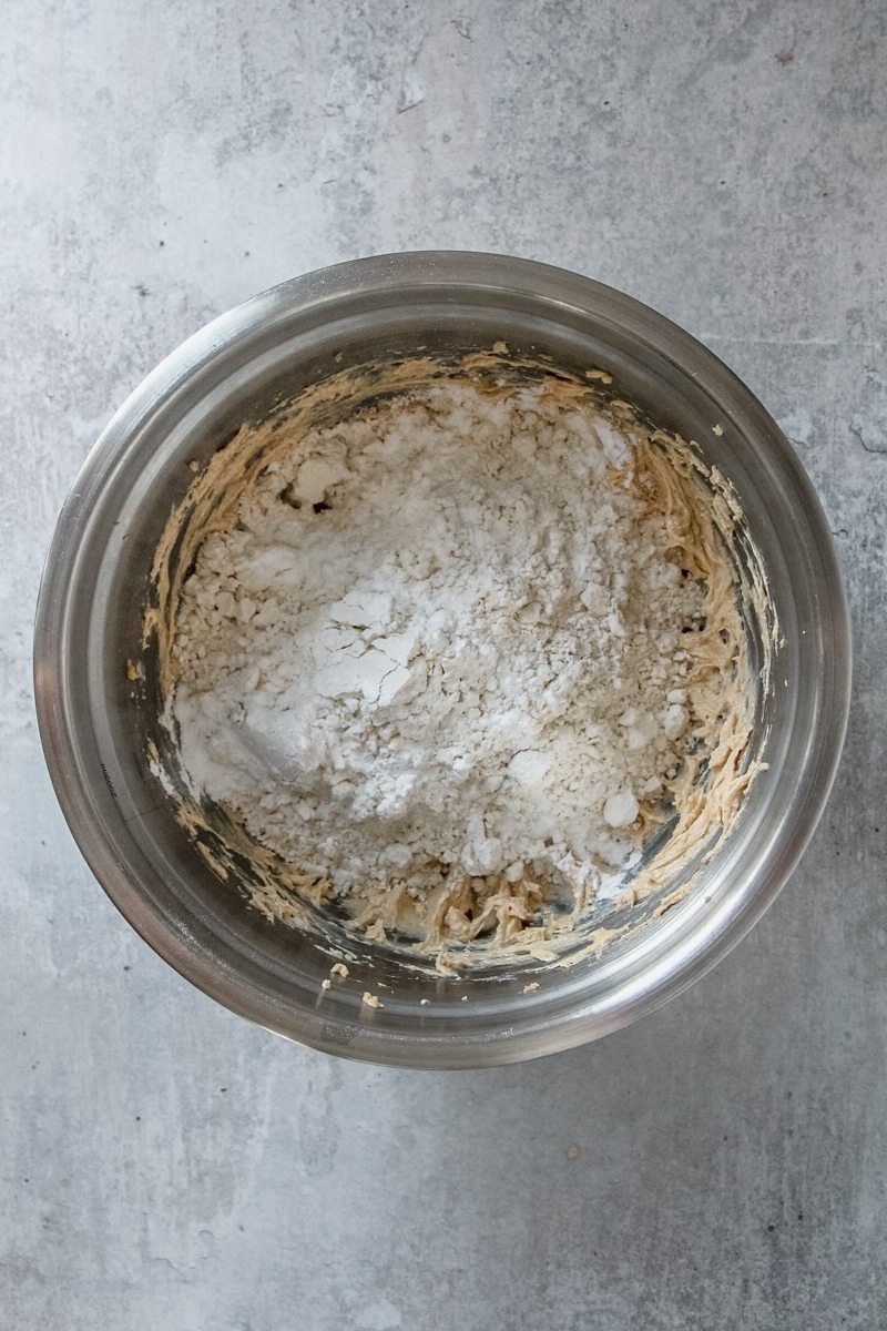 Dry ingredients sit in a stainless steel bowl on a light grey surface.