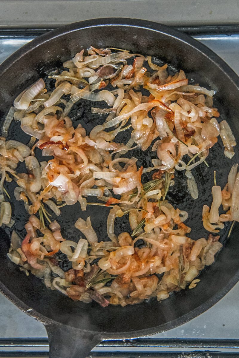 Caramelized onions sit in a cast iron skillet on a cooker.