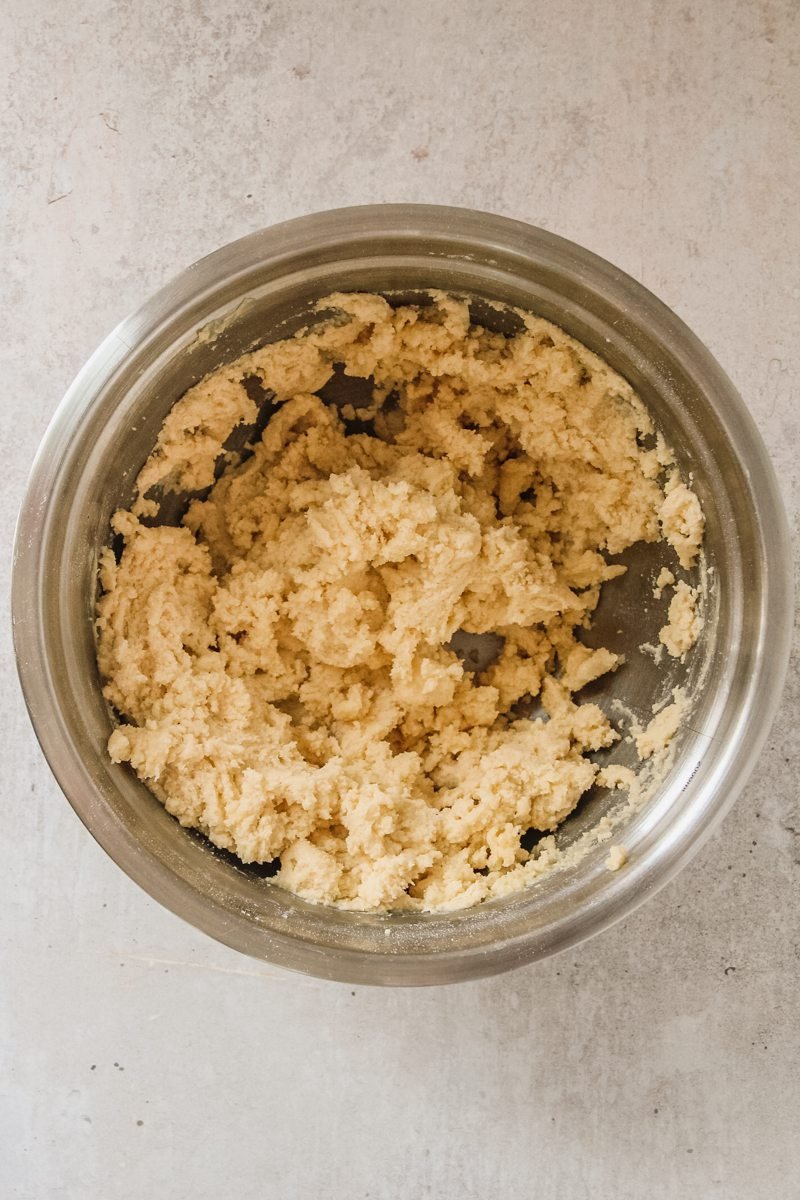 Dutch Butter Cake batter sit in a stainless steel bowl on a gray surface.