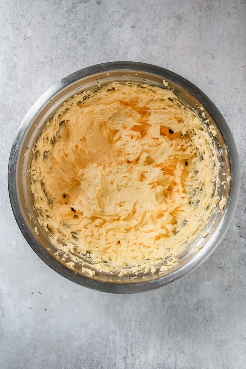 Whipped cake batter sits in a stainless steel bowl on a gray surface.