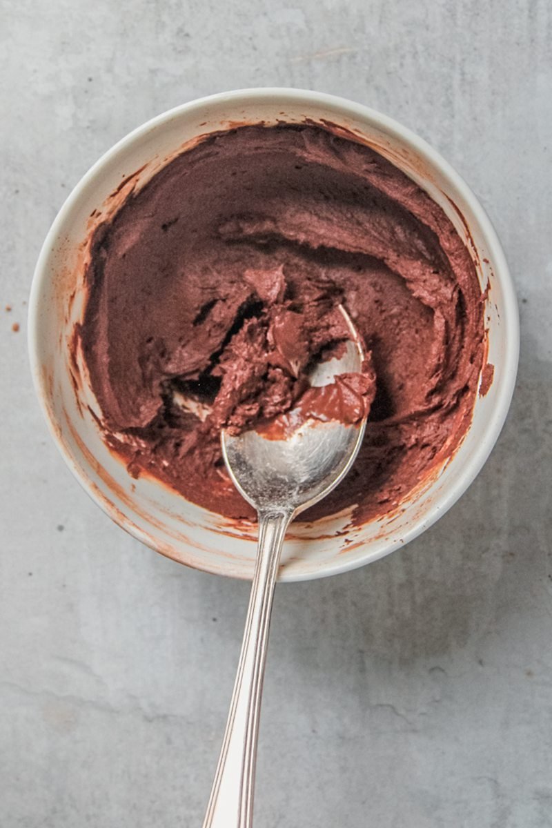 Coffee and cocoa powder sit stirred together in a white ceramic bowl on a gray surface.