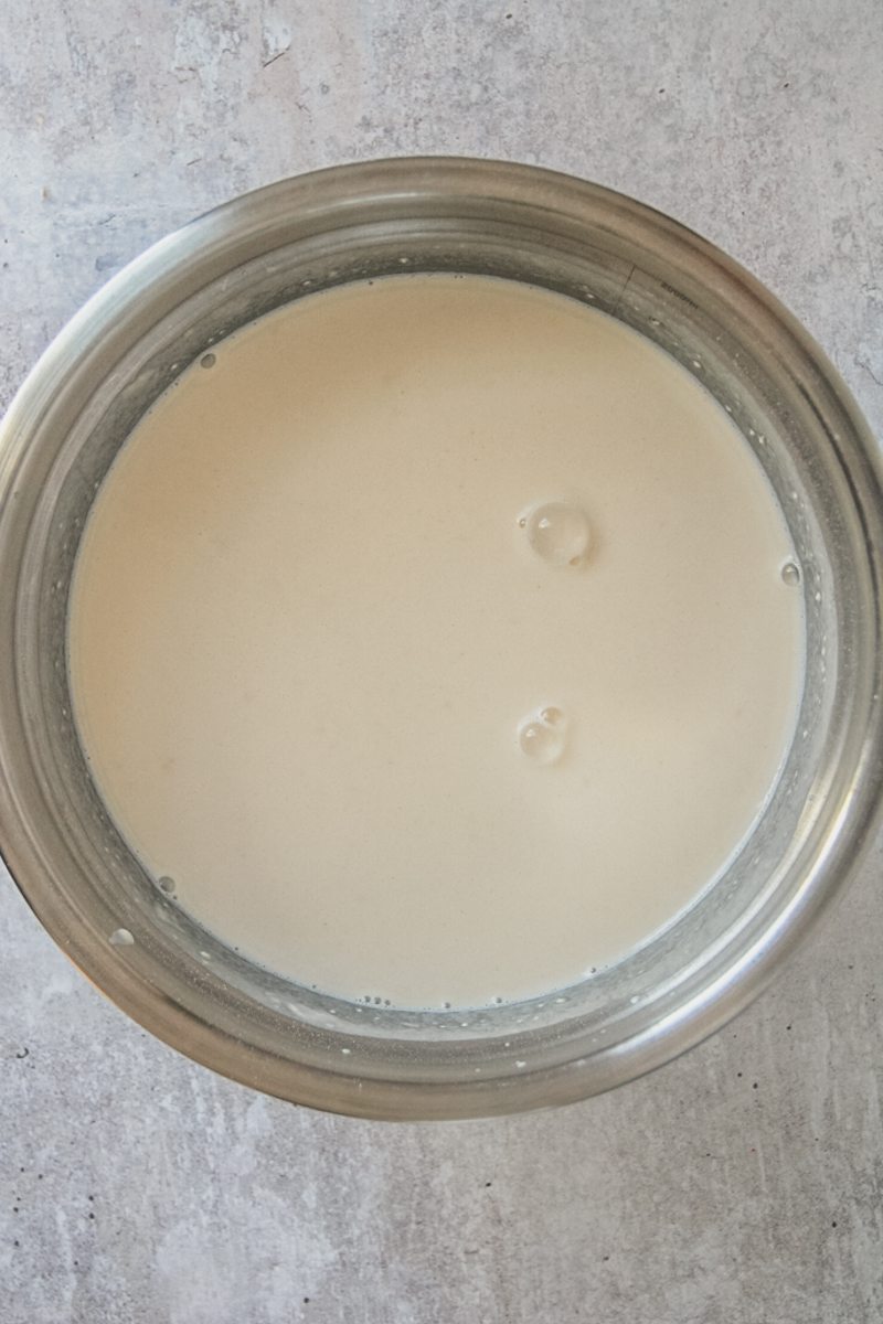 A base of pancake batter sits in a stainless steel bowl on a gray surface.