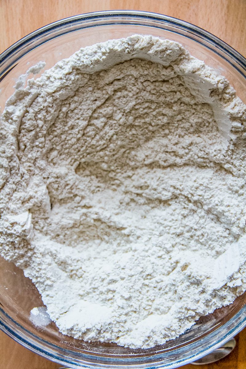Dry ingredients sit stirred together in a glass bowl.