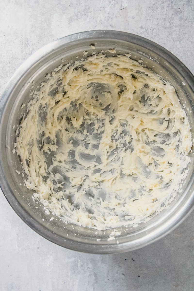 Whipped butter sits in a stainless steel bowl on a gray surface.