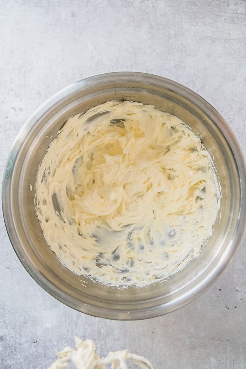 Whipped butter sits in a stainless steel bowl on a gray surface.