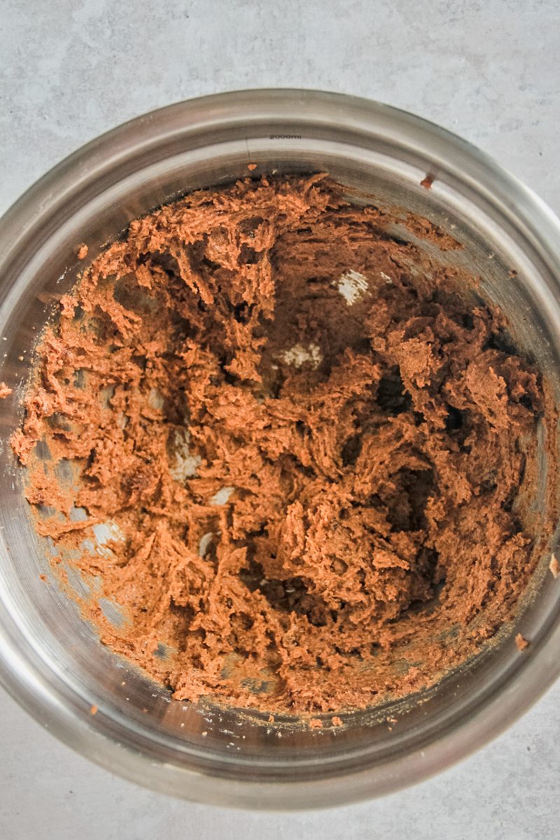 Whipped butter and brown sugars sit in a stainless steel bowl on a gray surface.