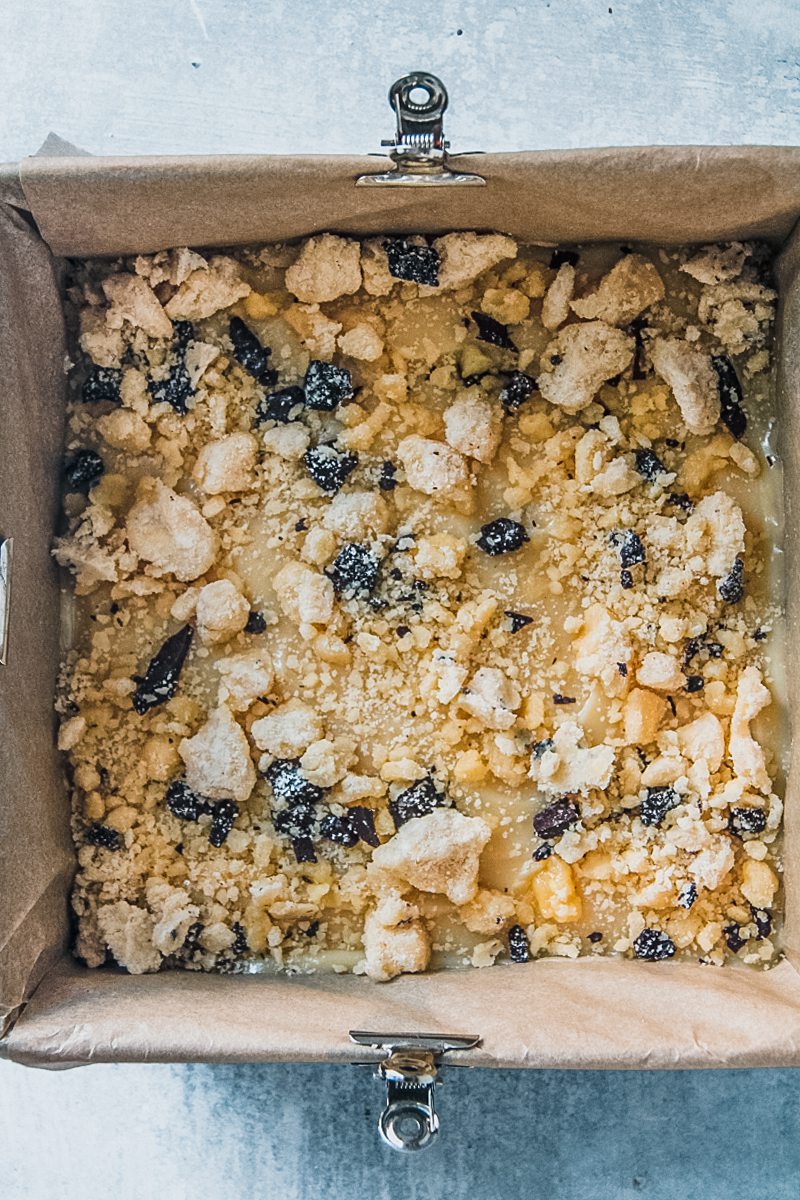 Unbaked tan slice sits in a lined square baking tin on a gray surface.