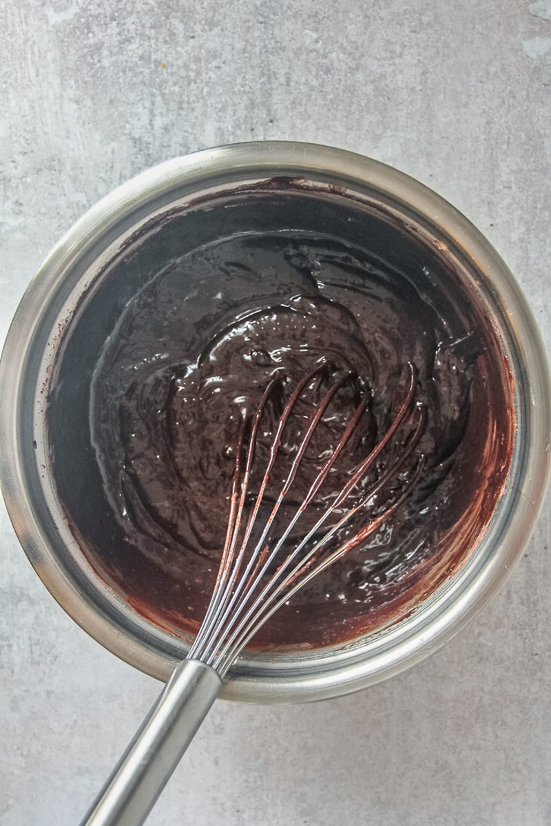 A brownie mixture sits in a stainless steel bowl on a gray surface.