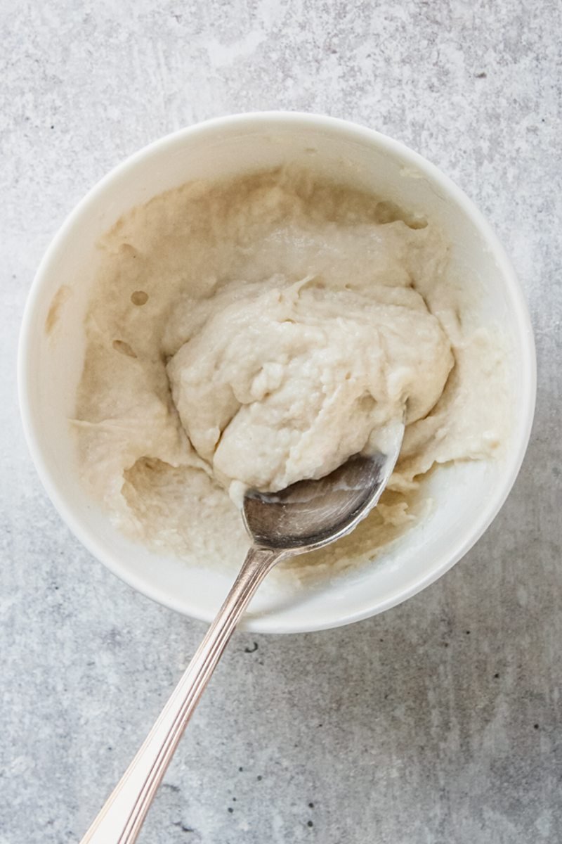 A cornflour roux sits in a white ceramic bowl on a gray surface.