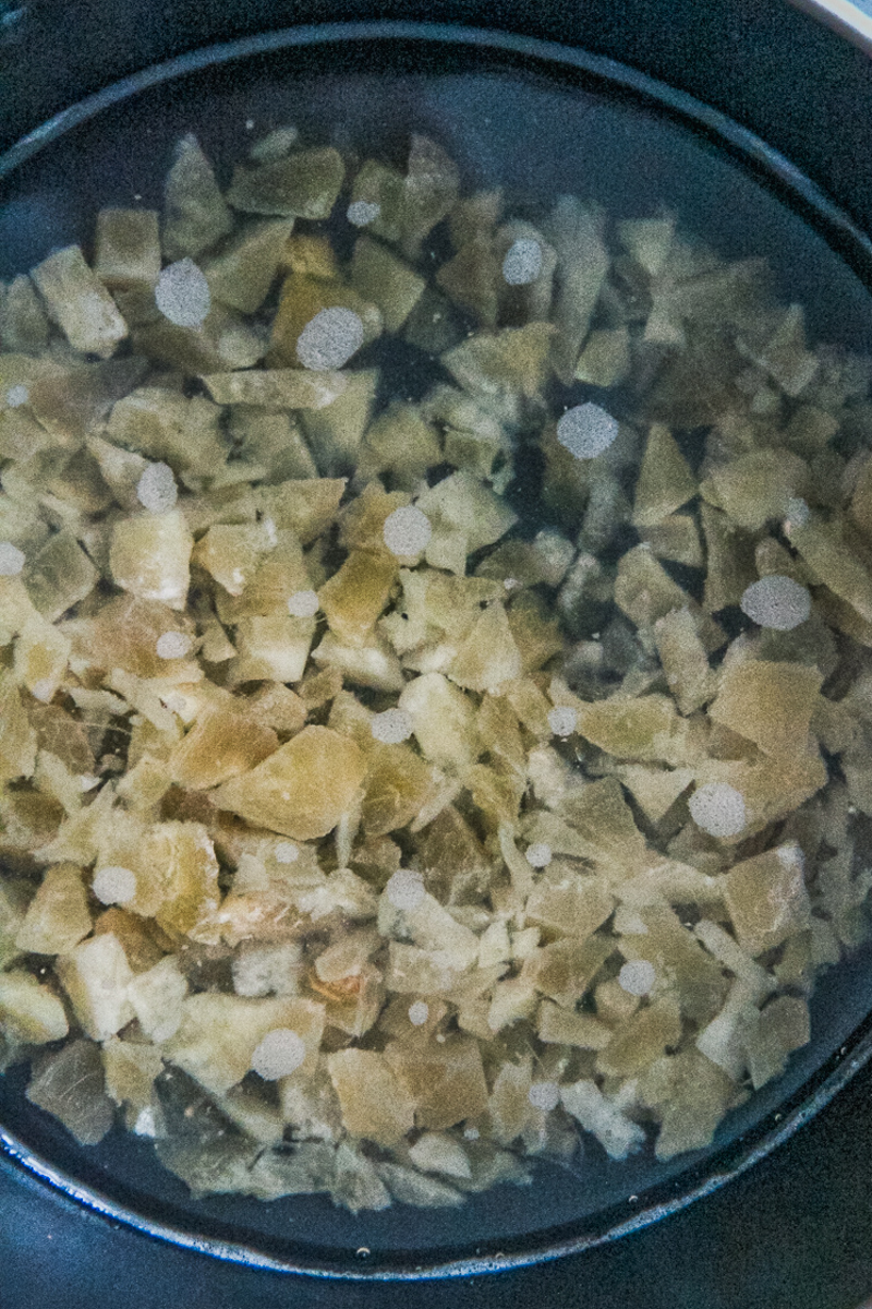 Crystallized ginger and water sit in a saucepan.