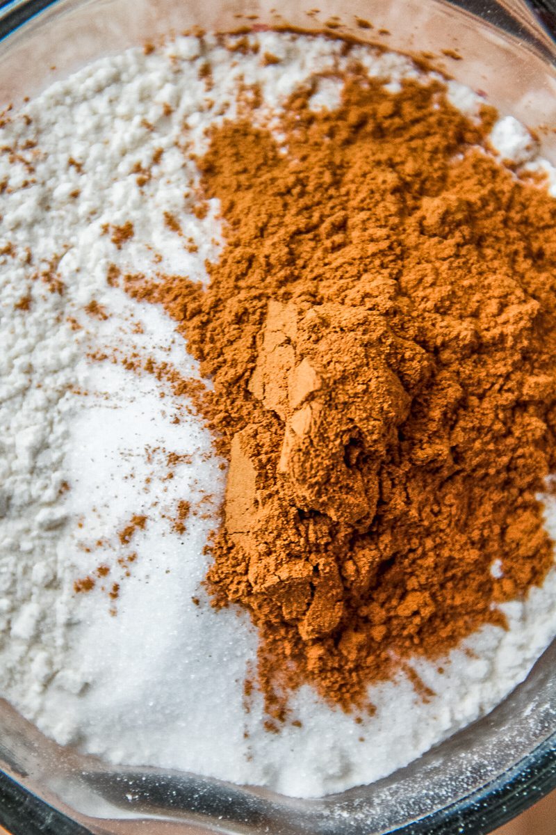 Ground cinnamon and other dry ingredients sit in a pyrex measuring cup.