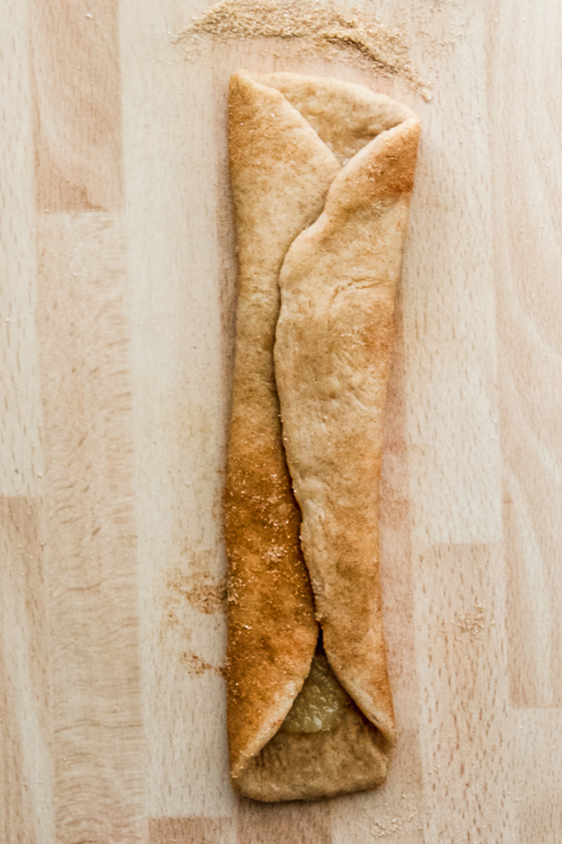 A Dutch ginger roll sits on a wooden surface folded over being being rolled into a scroll.