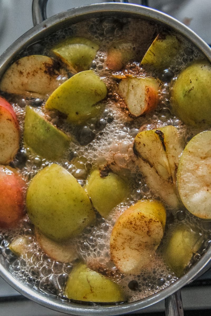 Simmering apples sit in a stainless steel pot on a cooker.